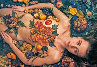 Sophie Dix draped with edibles lying on a dining table in "The Hour of the Pig".